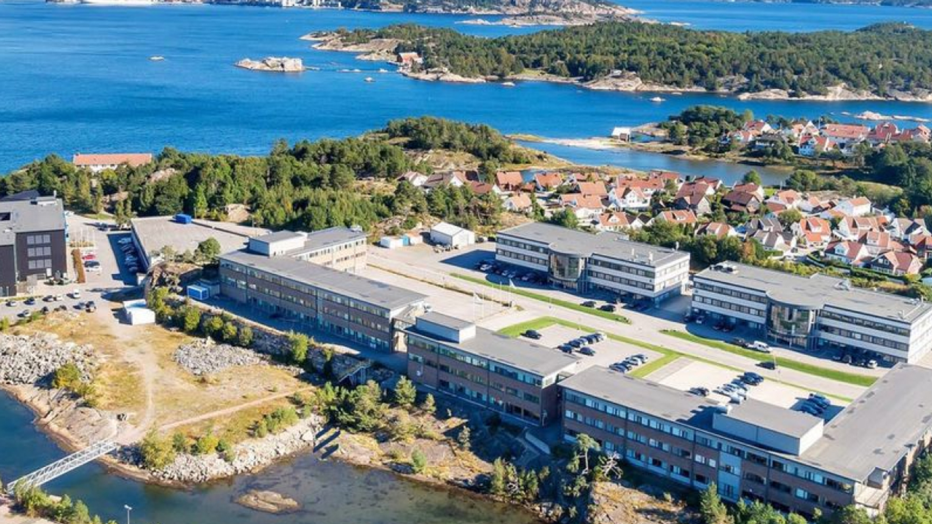 Dronebilde av et område i dagslys, med både by og hav i bildet. Foto.