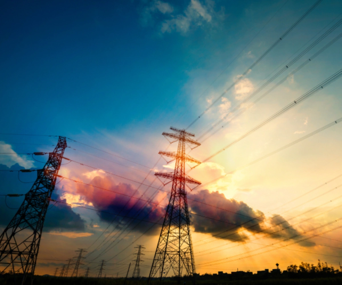 Froskeperspektiv av strømledninger mot himmelen i solnedgangen. Foto.