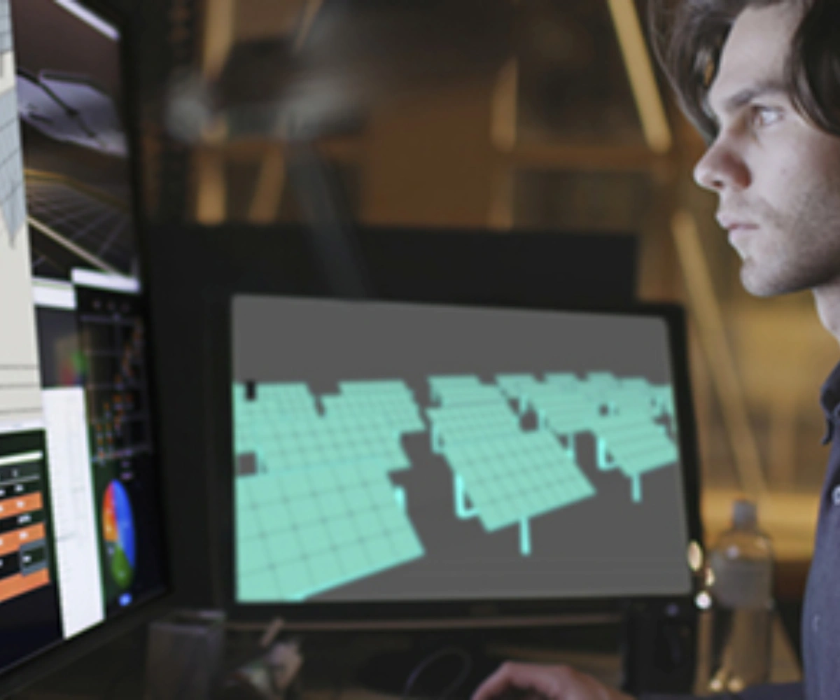 En person jobber foran flere skjermer med ulike data og informasjon. Bilde.