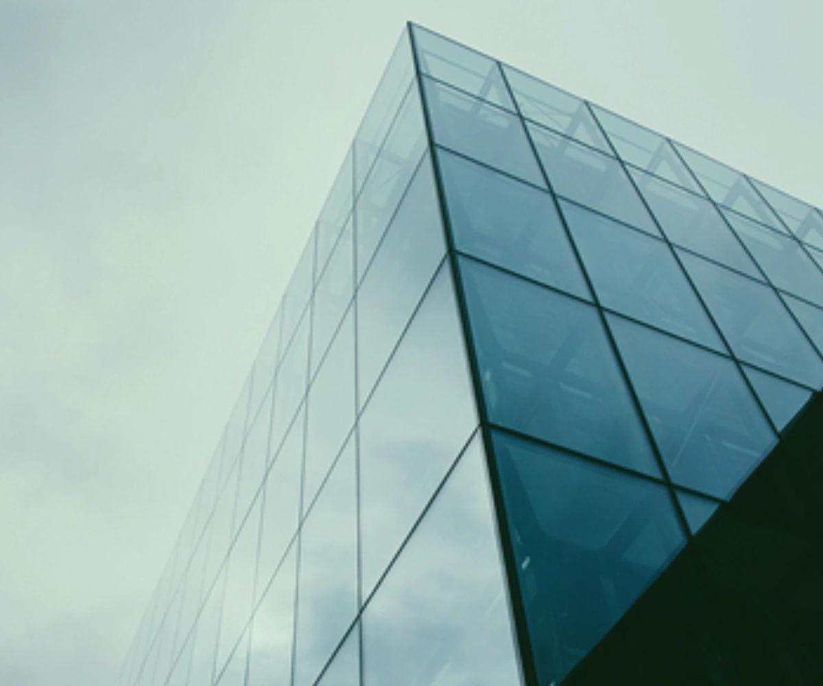 Froskeperspektiv av et glassbygg, med nærbilde av hjørnet på toppen av konstruksjonen. Bilde.