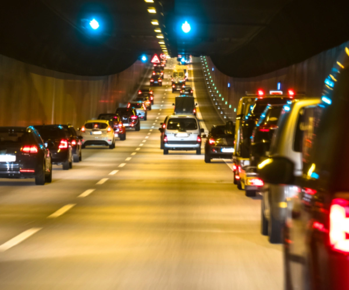 Biler står i lange rekker i en opplyst tunnel. Foto.